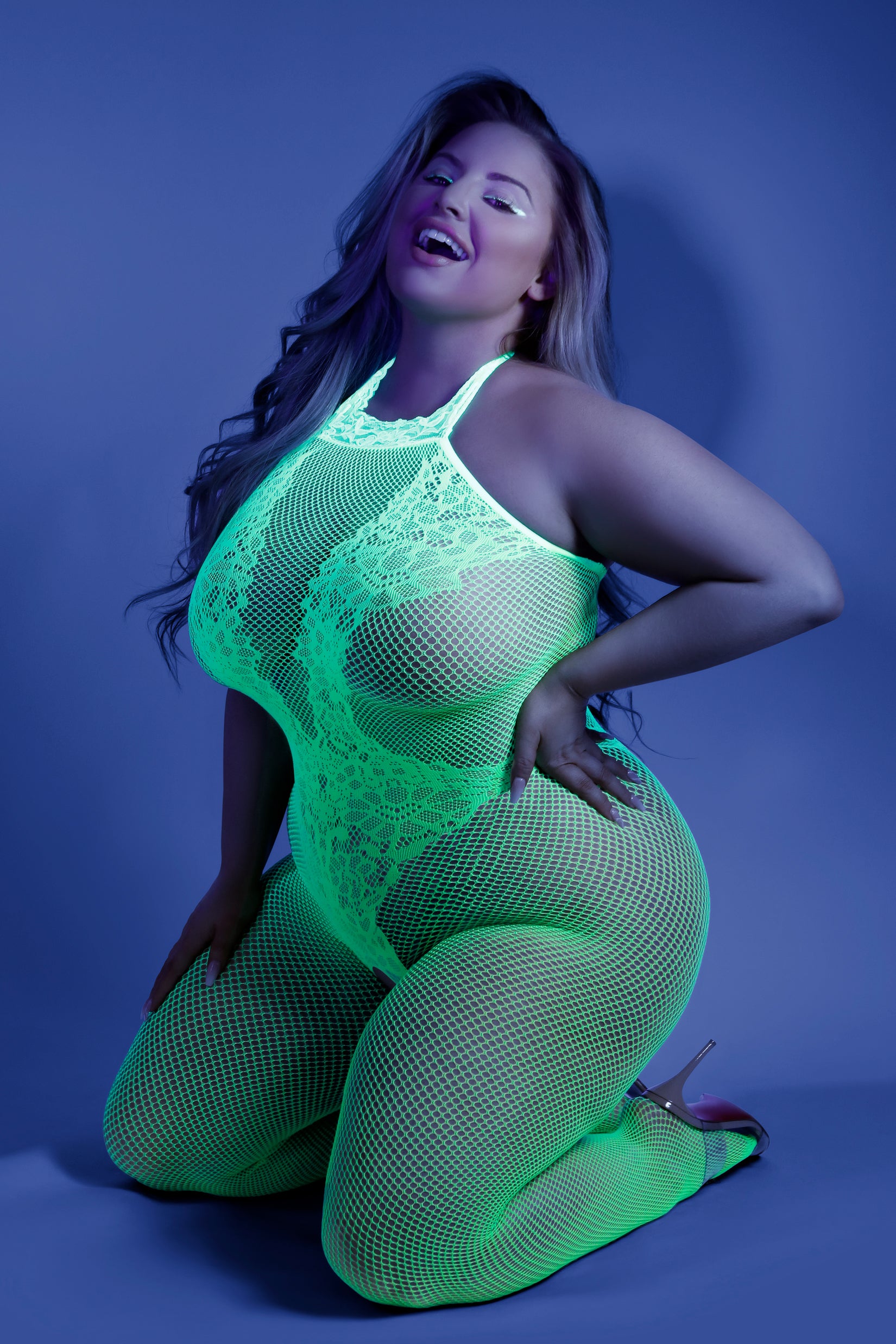 Plus size model kneeling in neon lace fishnet bodystocking by CT Lingerie Moonbeam Glow In the Dark BodySuit